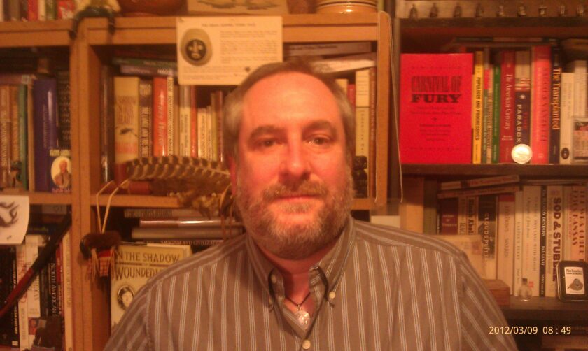 Man standing in front of bookshelves filled with books.